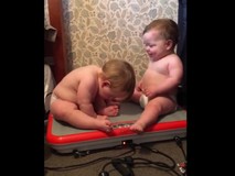 2 em bé ngồi trên máy rung lắc vui...