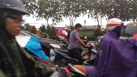 Mưa đổ xuống, người chạy xe máy ùn ùn dừng lại mặc áo mưa, ngay trong làn đường ô tô, và kẹt xe (đường Trường Chinh). Ảnh: Lâm Thông