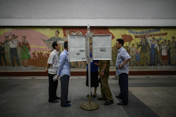 Người dân Bình Nhưỡng (Triều Tiên) đọc báo về cuộc thượng đỉnh lịch sử Mỹ-Triều, ngày 12-6. Ảnh: GETTY IMAGES