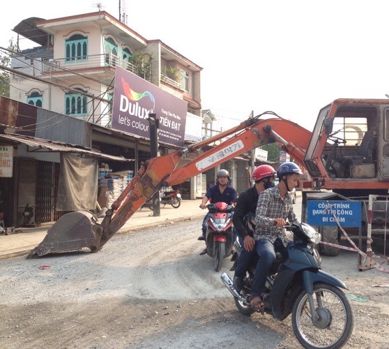 Muốn qua đường phải 'chui' dưới xe múc đất