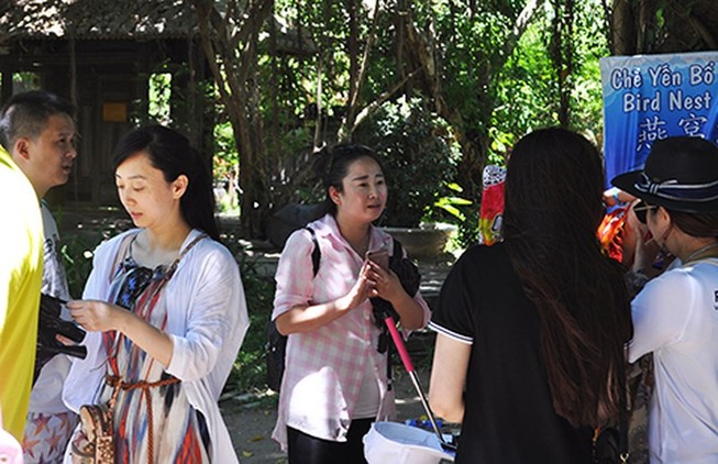 Một nữ HDV người Trung Quốc (mặc áo ca rô) đang giới thiệu cho một đoàn khách nước này tại một điểm du lịch ở Nha Trang. Ảnh minh họa: TẤN LỘC