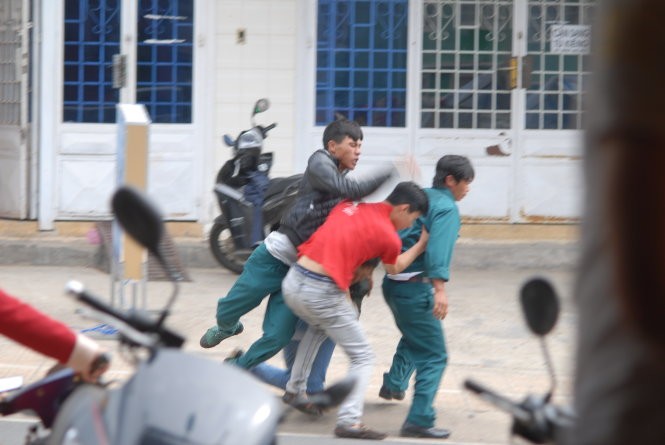 Lập tức người mặc trang phục dân quân tự vệ lao vào đánh đấm túi bụi người thanh niên mặc thường phục trước sự sửng sốt của nhiều người chứng kiến