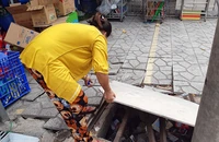 Nắp cống trước nhà (đường số 2, phường Bình Hưng Hòa B, quận Bình Tân) bị mất, chị Hoa tự đặt tấm ván và vài thanh sắt chắn tạm lên miệng cống để không nguy hiểm cho người đi đường.