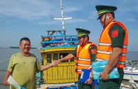 Hiểu được tầm quan trọng của việc chống khai thác IUU, nhiều ngư dân vui vẻ khi nhận tờ rơi tuyên truyền từ các chiến sĩ biên phòng. Ảnh: THUẬN VĂN