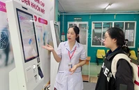Điều dưỡng Nguyễn Thị Thu hướng dẫn bệnh nhân đăng ký khám bệnh bằng ki-ốt thông minh tại BV quận Phú Nhuận. Ảnh: THẢO PHƯƠNG