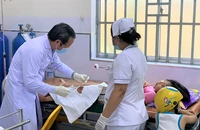 Bác sĩ Phòng khám vệ tinh Vĩnh Lộc B phối hợp với nhân viên y tế của Trạm y tế Vĩnh Lộc B xử lý vết thương cho một bệnh nhi. Ảnh: THẢO PHƯƠNG