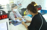 Cán bộ quận 1 hướng dẫn người dân làm thủ tục đăng ký kinh doanh trên mạng và sử dụng hệ thống định danh điện tử.