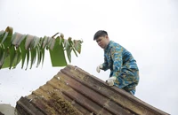 Các chiến sĩ Sư đoàn Không quân 372 sửa lại nhà cho người dân bị thiệt hại do vụ máy bay Su-22 rơi hôm 9-1. Ảnh: TN