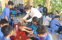 Ông Đinh Phú Cường, Hiệu trưởng Trường THCS Nguyễn Văn Luông, quận 6, đang tiếp phẩm cho học sinh trong bữa ăn bán trú. Ảnh: NGUYỄN QUYÊN
