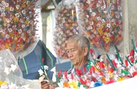 Ông Nguyễn Hóa đang tỉ mỉ làm ra những bông hoa giấy. Ảnh: N.DO
