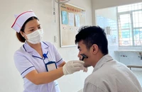 Điều dưỡng Nguyễn Thị Xuân cạo râu cho một nam bệnh nhân tâm thần. Ảnh: TRẦN NGỌC