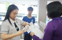 Giám thị kiểm tra giấy tờ trước khi thí sinh vào phòng thi tại Hội đồng thi TP.HCM. Ảnh: NGUYỄN QUYÊN