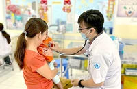 Bác sĩ Lý Hiển Khánh thăm khám cho bệnh nhi tại khoa Nhiễm - Thần kinh BV Nhi đồng 1. Ảnh: THẢO PHƯƠNG