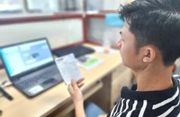 Một phụ huynh đang đóng học phí cho con qua phần mềm sau khi nhận được phiếu báo thu từ nhà trường. Ảnh: NGUYỄN QUYÊN