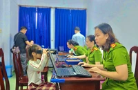 Công an phường Thủ Đức hỗ trợ em bé bước "quét móng mắt" để làm CCCD. Ảnh: PHẠM HẢI