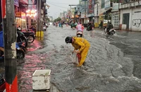Các công nhân vớt rác, giúp khu chợ Thủ Đức thoát nước nhanh sau cơn mưa lớn
