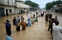 Người di dời lội qua một khu vực ngập nước ở thành phố Peshawar, tỉnh Khyber Pakhtunkhwa (Pakistan) ngày 27-7. Ảnh: CNN