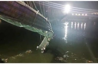 Nhiều người rớt xuống sông Machchu bên dưới khi cây cầu treo ở bang Gujarat, miền tây Ấn Độ bị sập ngày 30-10. Ảnh: REUTERS