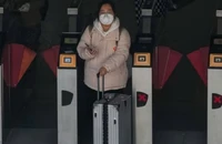Một người phụ nữ đeo khẩu trang ra khỏi ga tàu điện ngầm ở Bắc Kinh, Trung Quốc vào ngày 13-12. Ảnh: AP 