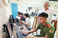 Người dân được cán bộ công an hỗ trợ làm tờ khai cấp hộ chiếu phổ thông. Ảnh: NGUYỄN TÂN