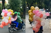 Chở người ngồi sau xe cầm nhiều bong bóng có vi phạm pháp luật?
