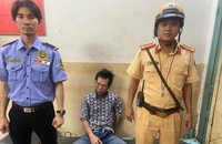 Đại úy Trần Hoài Nam, cán bộ Đội CSGT Bến Thành đưa người đàn ông về trụ sở công an phường. Ảnh: PC08