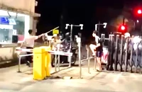 Người mang trang phục bảo vệ cầm gậy đánh nam thanh niên trước cổng ký túc xá làng đại học