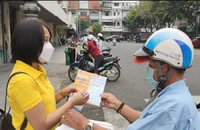 Nhân viên bưu điện tư vấn người dân về quyền lợi khi tham gia BHXH BHYT hộ gia đình. Ảnh: NGUYỄN HIỀN