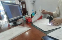 Công chứng viên đang kiểm tra giấy tờ bất động sản. Ảnh: NGUYỄN HIỀN