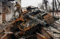 Một người đàn ông nhảy khỏi chiếc xe tăng T-72 của Nga bị phá hủy tại làng Yahidne, Ukraine ngày 20-4-2022. Ảnh: REUTERS