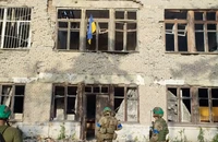 Các binh sĩ Ukraine đứng trước một tòa nhà có treo cờ Ukraine khi nước này tuyên bố giải phóng làng Blahodatne (đông nam Ukraine) ngày 11-6. Ảnh: REUTERS