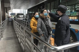 Hành khách được kiểm tra thân nhiệt trước khi lên xe ở Thượng Hải. Ảnh: REUTERS