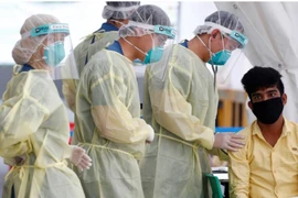 Nhân viên y tế lấy mẫu xét nghiệm cho một công nhân nhập cư tại ký túc xá ở Singapore ngày 15-5. Ảnh: REUTERS 