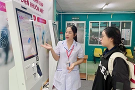 Điều dưỡng Nguyễn Thị Thu hướng dẫn bệnh nhân đăng ký khám bệnh bằng ki-ốt thông minh tại BV quận Phú Nhuận. Ảnh: THẢO PHƯƠNG