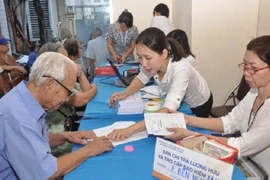 Nhân viên bưu điện chi trả lương hưu cho người dân. Ảnh: V.LONG
