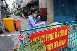 Người dân trong hẻm bị phong tỏa trên đường Trường Sa (quận Phú Nhuận, TP.HCM) khử khuẩn thùng hàng từ bên ngoài gửi vào.