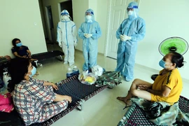 Sư cô Nhuận Bình (người mặc đồ bảo hộ ở giữa) đến các phòng bệnh nhẹ để động viên bệnh nhân.