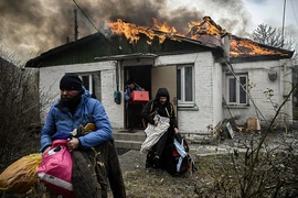 Người dân Ukraine tại TP Irpin gần thủ đô Kiev (Ukraine) gom hành lý rời căn nhà đang cháy vì bị trúng pháo ngày 4-3.