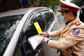 CSGT dán thông báo vi phạm dừng đỗ lên kính ô tô. Ảnh: TP