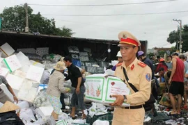 Xe tải lật, CSGT cùng dân giúp gom hàng