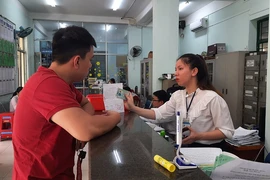 Công chức Tư pháp - Hộ tịch phường 3 (Gò Vấp) hướng dẫn người dân làm thủ tục khai sinh. Ảnh: TRÚC PHƯƠNG