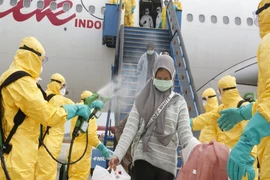 Nhân viên y tế phun thuốc khử trùng cho những người Indonesia được sơ tán khỏi Trung Quốc tại sân bay quốc tế Hang Nadim, quần đảo Riau ngày 16-2. Ảnh: BỘ NGOẠI GIAO INDONESIA 