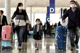 Hành khách đeo khẩu trang di chuyển vào sân bay quốc tế Hong Kong ngày 22-1. Ảnh: REUTERS