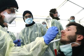 Nhân viên y tế xét nghiệm một người nghi nhiễm COVID-19 ở TP Munich, Đức ngày 29-3. Ảnh: AFP