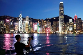 Một người đàn ông đeo khẩu trang chụp ảnh bên kia cảng Victoria sau khi dịch COVID-19 bùng phát ở Hong Kong, ngày 28 -7 năm 2020. Ảnh: REUTERS