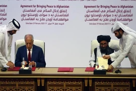 Trưởng đoàn đàm phán Taliban - ông Mullah Abdul Ghani Baradar ký thỏa thuận với đặc phái viên Mỹ về vấn đề Afghanistan MỹZalmay Khalilzad vào ngày 29-2-2020 tại Doha (Qatar). Ảnh: REUTERS/Ibraheem al Omari