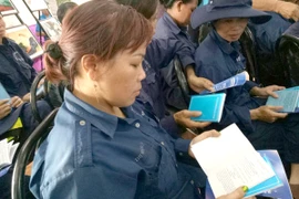 Các công nhân đọc cẩm nang pháp lý lao động. Ảnh: TRÚC PHƯƠNG