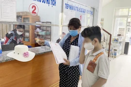Tuấn cùng mẹ đến UBND phường 12, quận Bình Thạnh nhận giấy khai sinh sau nhiều năm chờ đợi. Ảnh: HỮU ĐĂNG