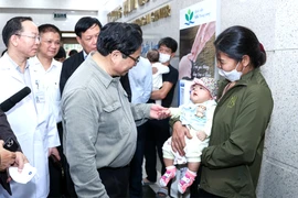 Thủ tướng hỏi thăm sức khỏe một trẻ đang khám tại BV Nhi trung ương trong thời điểm thời tiết chuyển mùa. Ảnh: VGP/NHẬT BẮC