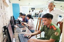 Người dân được cán bộ công an hỗ trợ làm tờ khai cấp hộ chiếu phổ thông. Ảnh: NGUYỄN TÂN